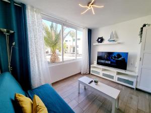een woonkamer met een blauwe bank en een tv bij Apartamento DINO 10 PLAYA ROCA in Costa Teguise