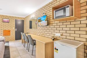 a kitchen with a bar and a tv on a brick wall at Stagecoach Inn Motel in Tamworth