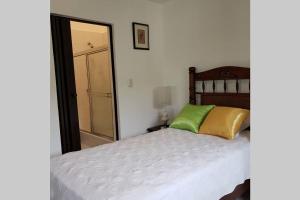 um quarto com uma cama com uma almofada verde e amarela em Great location, right downtown Puerto plata . em San Felipe de Puerto Plata