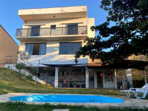 una casa con piscina frente a ella en Casa com piscina fundo pra represa e AR Condicionado CasinhaBrancaDeVaranda en Ijaci