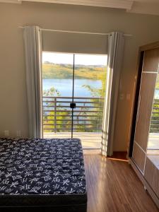 une chambre avec un lit et une grande fenêtre dans l'établissement Casa com piscina fundo pra represa e AR Condicionado CasinhaBrancaDeVaranda, à Ijaci