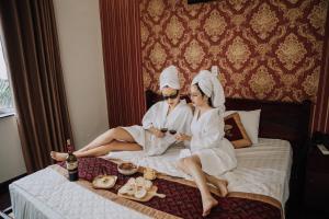 deux personnes vêtues de blanc assises sur un lit dans l'établissement Diamond Hotel Thai Binh, à Thái Bình 63 autres photos
