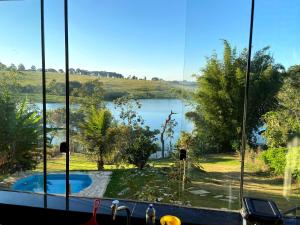 a view of a lake from a kitchen window at Casa com piscina fundo pra represa e AR Condicionado CasinhaBrancaDeVaranda in Ijaci