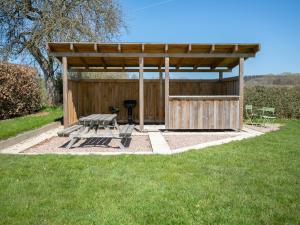 a picnic shelter with a picnic table and a grill at Spacious holiday home in the Ardennes with sauna in Nieder-Emmels