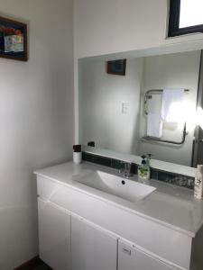 La salle de bains blanche est pourvue d'un lavabo et d'un miroir. dans l'établissement Tophouse Mountainview Cottages, à Saint Arnaud