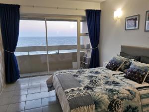 a bedroom with a bed with a view of the ocean at Stella Maris 123 in Amanzimtoti