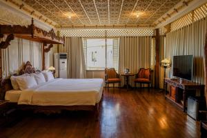 a bedroom with a large bed and a television at Las Casas Filipinas de Acuzar in Bagac