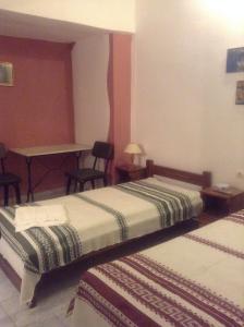 two beds in a room with a table and chairs at Niki Rooms in Tinos Town