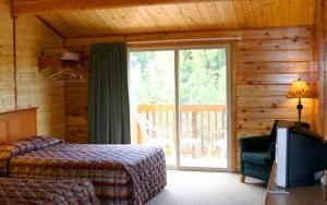- une chambre avec un lit et une porte coulissante en verre dans l'établissement Denali Grizzly Bear Resort, à McKinley Park