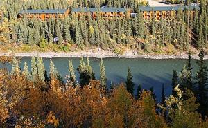 a river with trees and a train on it at Denali Grizzly Bear Resort in McKinley Park