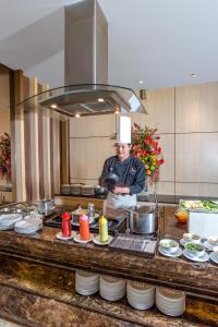 a chef standing in a kitchen preparing food at Orchardz Hotel Industri Jakarta Kemayoran in Jakarta