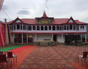 a large building with a red roof and a red carpet at Madhan Palace Homestay in Dharmpur