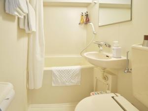 Baño blanco con lavabo y aseo en Pod Select Hotel Shinjuku, en Tokio