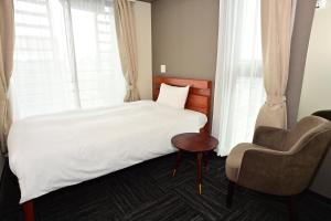 a bedroom with a bed and a chair and a window at BRILLIANCE Hotel in Nagoya