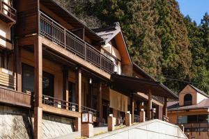 a large wooden building with a mountain in the background at Shima Onsen Kashiwaya Ryokan in Nakanojo