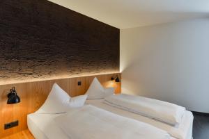 um quarto com 2 camas e almofadas brancas em Fuxbau em Stuben am Arlberg