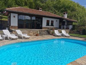 a swimming pool with chairs and a house at АРНАТА КЪЩА in Yakovtsi
