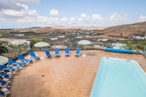 een zwembad met blauwe stoelen en parasols bij Finca Bellavista in Teguise
