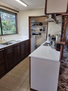 uma cozinha com um balcão branco e um lavatório em Catlins Lake Sanctuary em Owaka