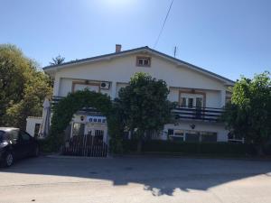 een wit huis met een auto ervoor geparkeerd bij Guest House Major in Arandjelovac