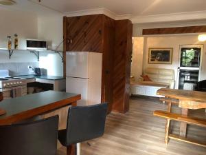 eine Küche mit einem Kühlschrank und einem Tisch mit Stühlen in der Unterkunft Fun Times in Uki