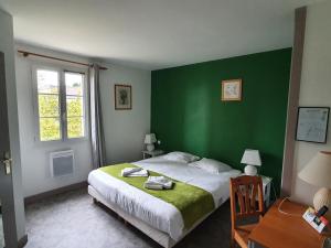 ein Schlafzimmer mit einer grünen Wand und einem Bett in der Unterkunft Hôtel Restaurant La Promenade in Gourdon-en-quercy