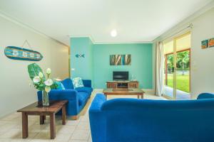 a living room with blue couches and a tv at Island Time Villas in Titikaweka