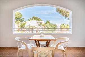 een tafel en stoelen in een kamer met een groot raam bij Apartamentos Karin 1ºc in Cala d´Or