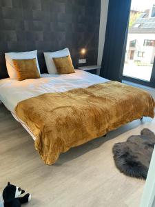 a large bed with a brown blanket on top of it at Gods Heide in Hasselt