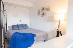 Dormitorio blanco con cama con almohadas azules en Apartamento junto a la playa con piscina y parking, en Punta Umbría