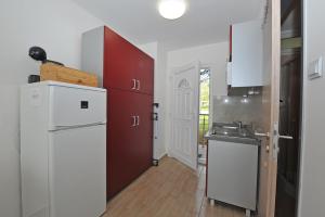 kuchnia z białą lodówką i czerwonymi szafkami w obiekcie Bella Rosa Apartman w Balatonfüred
