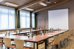 einen Konferenzraum mit Tischen, Stühlen und einem Whiteboard in der Unterkunft JUFA Hotel Grundlsee in Grundlsee