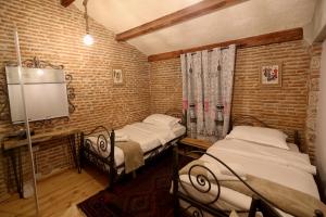 科爾察的住宿－Le Petit Secret, Korce, Albania，砖墙客房中的两张单人床