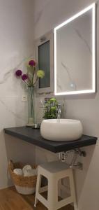 een badkamer met een wastafel, een spiegel en bloemen bij Sandra Rooms in Alicante