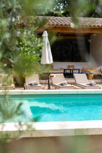 a pool with a table and an umbrella and chairs at mas des pampres in Cabannes
