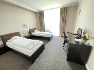 a hotel room with two beds and a desk at HOTEL OPAL Zalau in Zalău