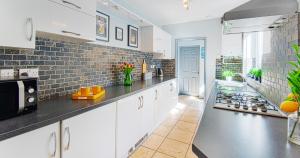 a kitchen with white cabinets and a brick wall at The Bishophill Gathering York - Sleeps Up To 12 in York