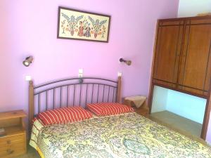 a bedroom with pink walls and a bed with red pillows at Dionysia Studios in Kefalos