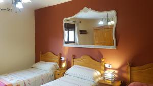 1 dormitorio con 2 camas y espejo en Casa Castel Turismo Rural, en Serrate