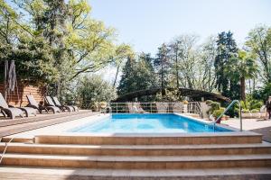 a swimming pool with some chairs and a bridge at Hotel Romanov in Sochi