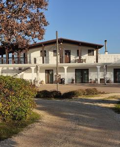 a large white house with a balcony and a road at Supramurgia Agribistrot in Cassano delle Murge