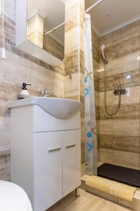 een badkamer met een witte wastafel en een douche bij Lili Apartman in Harkány