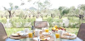 einen Tisch mit einem Frühstück mit Obst und Orangensaft in der Unterkunft Corfu Olivia Apartments in Moraḯtika