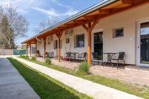 a covered patio with tables and chairs on a house at Lili Apartman in Harkány