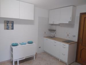 una cocina con armarios blancos y fregadero en Nonna Libera monolocale, en Rodi Garganico