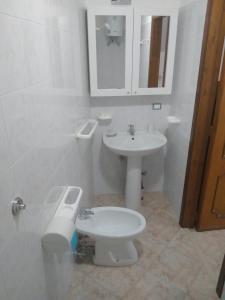 Baño blanco con aseo y lavamanos en Nonna Libera monolocale, en Rodi Garganico