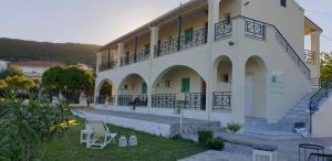 ein großes weißes Gebäude mit einem Balkon und Stühlen in der Unterkunft Corfu Olivia Apartments in Moraḯtika