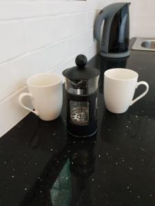 zwei Kaffeetassen stehen auf einer Theke neben einer Kaffeemaschine in der Unterkunft Corfu Olivia Apartments in Moraḯtika