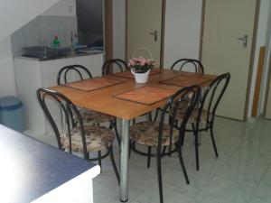 a wooden table with four chairs and a kitchen at Makai Apartman in Hajdúszoboszló