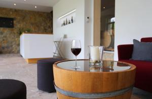 ラウダ・ケーニヒスホーフェンにあるBENZ Weingut & Weinhotelのワイン1杯(客室内のテーブルに座る)